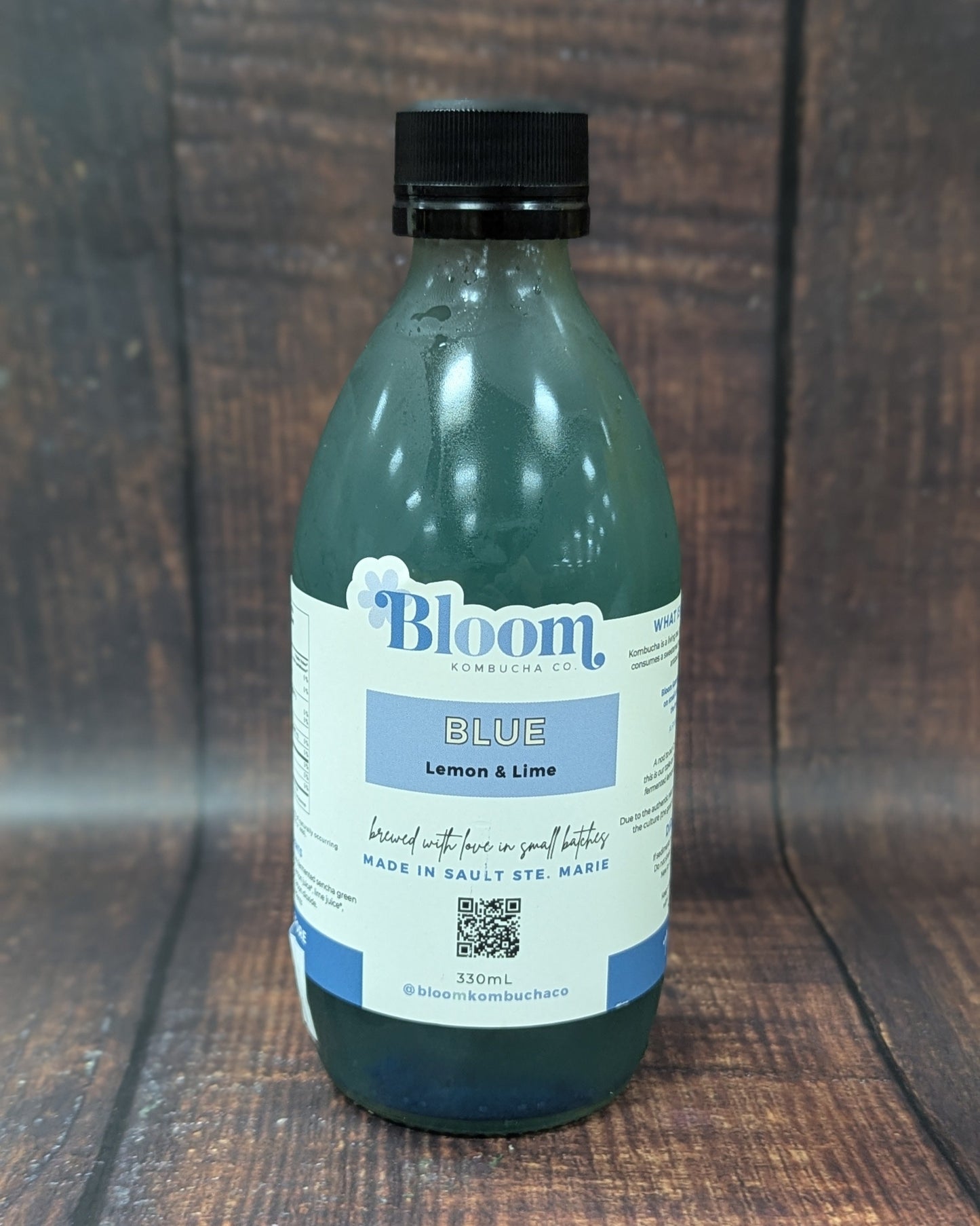 Bottle of Bloom Blue Lemon & Lime kombucha on a wooden surface