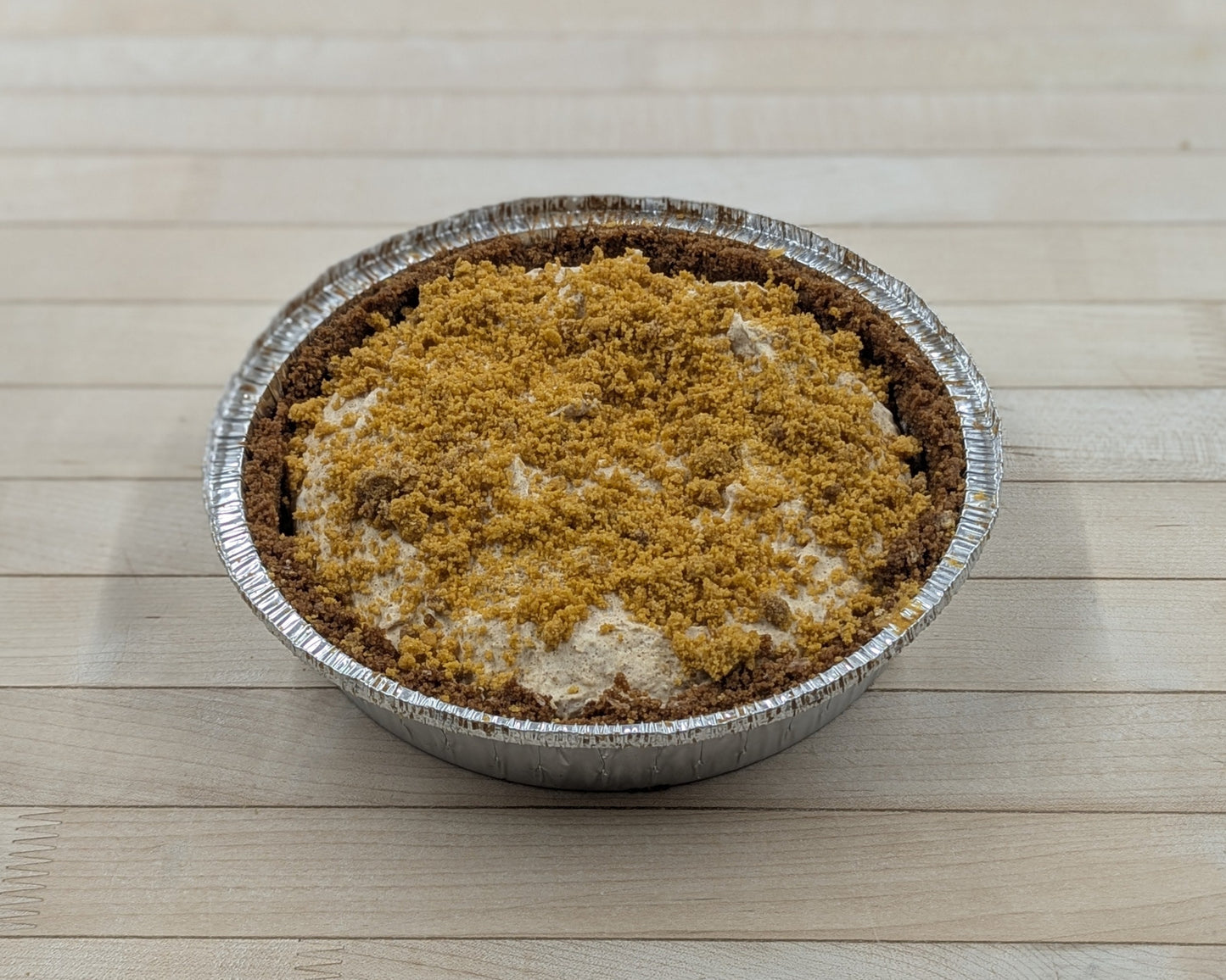 Small metal pie tin with a pumpkin spice cheesecake on a wooden surface