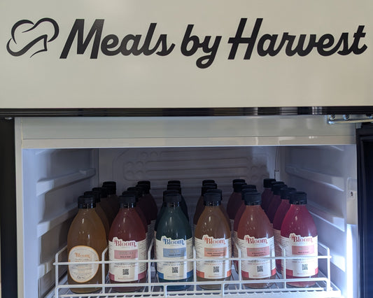Refrigerator with 'Meals by Harvest' branding and various bottles inside.
